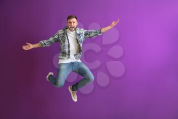 Jumping young man on color background�