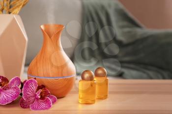 Aroma oil diffuser with bottles on table in room�