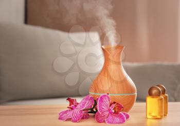 Aroma oil diffuser with bottles on table in room�