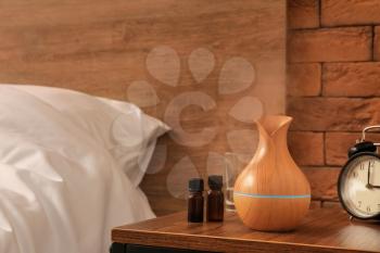 Aroma oil diffuser with bottles on table in bedroom�