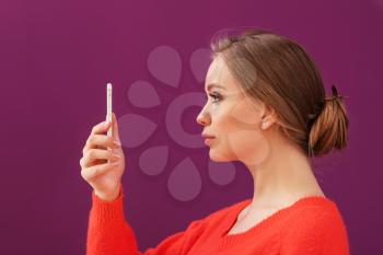 Young woman taking selfie with mobile phone on color background�