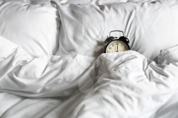 Alarm clock on bed in morning�