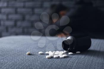 Overturned bottle with pills and depressed man on background. Suicide awareness concept�