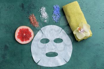 Sheet facial mask with sea salt and towel on color background�