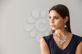 Young woman with beautiful jewelry on light background�