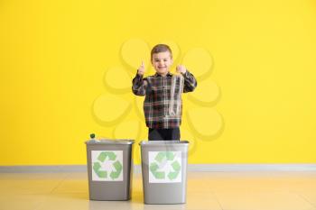 Little boy throwing garbage into trash bins near color wall. Concept of recycling�