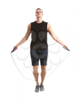 Sporty young man jumping rope against white background�