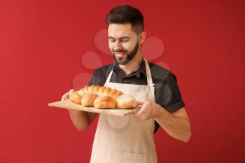 Baker with fresh bread on color background�