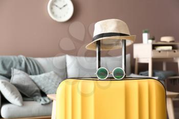 Packed suitcase, hat and sunglasses in room. Travel concept�