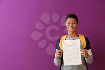African-American boy with answer sheet for school test on color background�