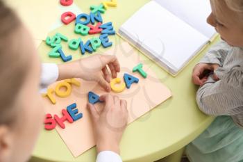 Little girl with speech therapist composing words of letters in office�