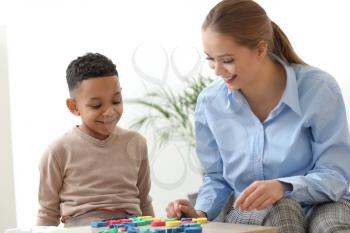 Little boy with speech therapist composing words of letters in office�