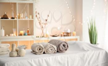 Soft towels with herbal bags on table in spa salon�