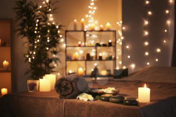 Massage stones with towel and candles on table in spa salon�