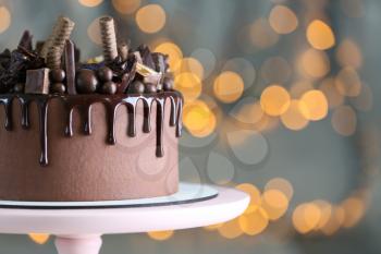 Stand with tasty chocolate cake against defocused lights�