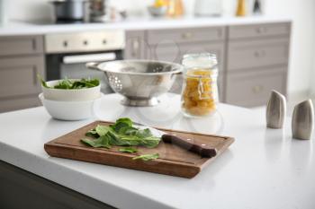 Fresh herbs with cutting board on table in kitchen�