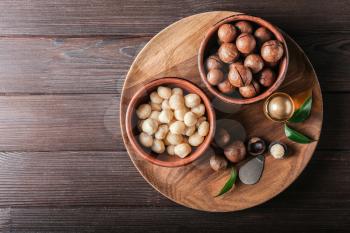 Bowls with macadamia nuts and oil on wooden table�