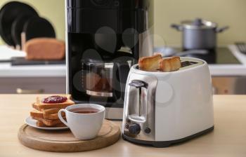 Toaster with bread slices and coffee machine on table�