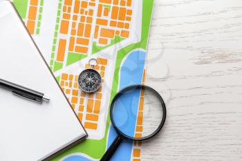 Map with compass and magnifier on white table�