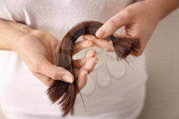 Woman with hair strand on light background, closeup. Concept of donation�