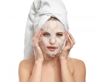 Beautiful young woman with sheet facial mask on white background�