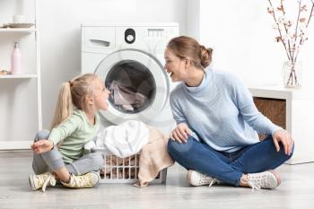 Young woman and her little daughter playing at home on laundry day�