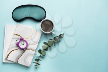 Composition with sleep mask, notebooks, clock and coffee on color background�