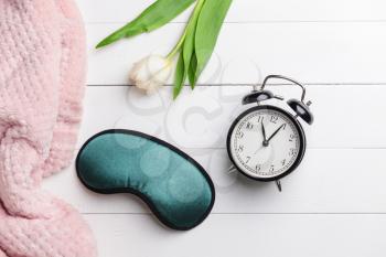 Composition with sleep mask, clock and flower on wooden background�