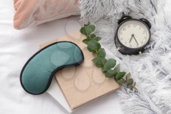 Sleep mask, notebooks and clock on bed�