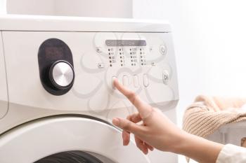 Woman switching on washing machine, closeup�