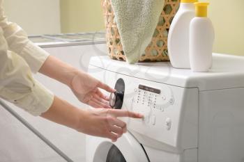Woman switching on washing machine�