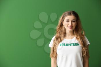 Young female volunteer on color background�