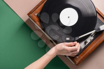 Hand of woman switching on record player with vinyl disc�