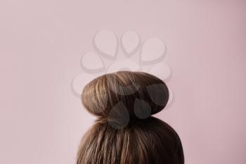 Young woman with hair bun on color background 