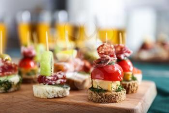 Tasty canapes on wooden board, closeup�
