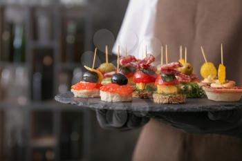 Chef holding slate plate with tasty canapes, closeup�