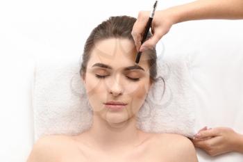 Young woman undergoing eyebrow correction procedure in beauty salon�