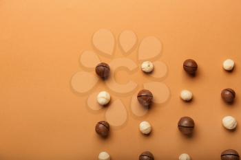 Many macadamia nuts on color background 