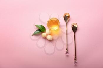 Spoons and macadamia oil on color background�