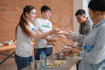 Young volunteers giving food to poor people�