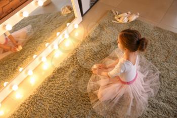 Cute little ballerina sitting in front of mirror at home�