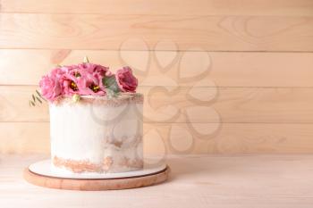Sweet cake with floral decor on wooden background�