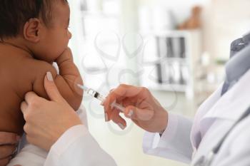 Pediatrician giving little baby an injection in clinic�