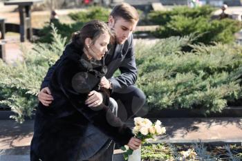 Couple putting flowers on grave of their relative at funeral�