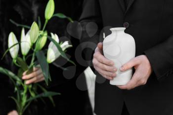Couple with mortuary urn and flowers at funeral�