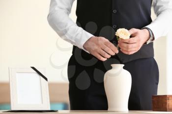 Man with mortuary urn and flower at funeral�