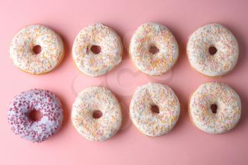 Lilac doughnut among white ones on color background. Concept of uniqueness�