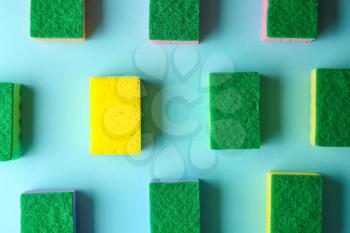 Yellow sponge among green ones on color background. Concept of uniqueness�
