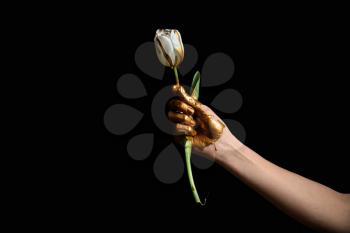 Painted hand with tulip flower against dark background�