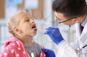 Pediatrician examining little girl in clinic�